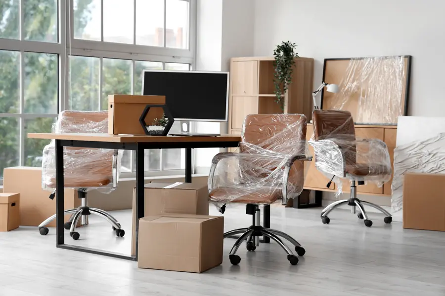 Büro mit eingepackten Stühlen und Umzugskartons