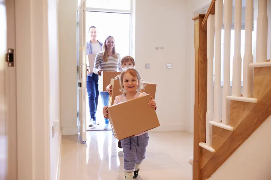 Familie trägt Umzugskartons ins neue Zuhause