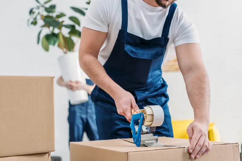 Umzugshelfer verklebt einen Karton